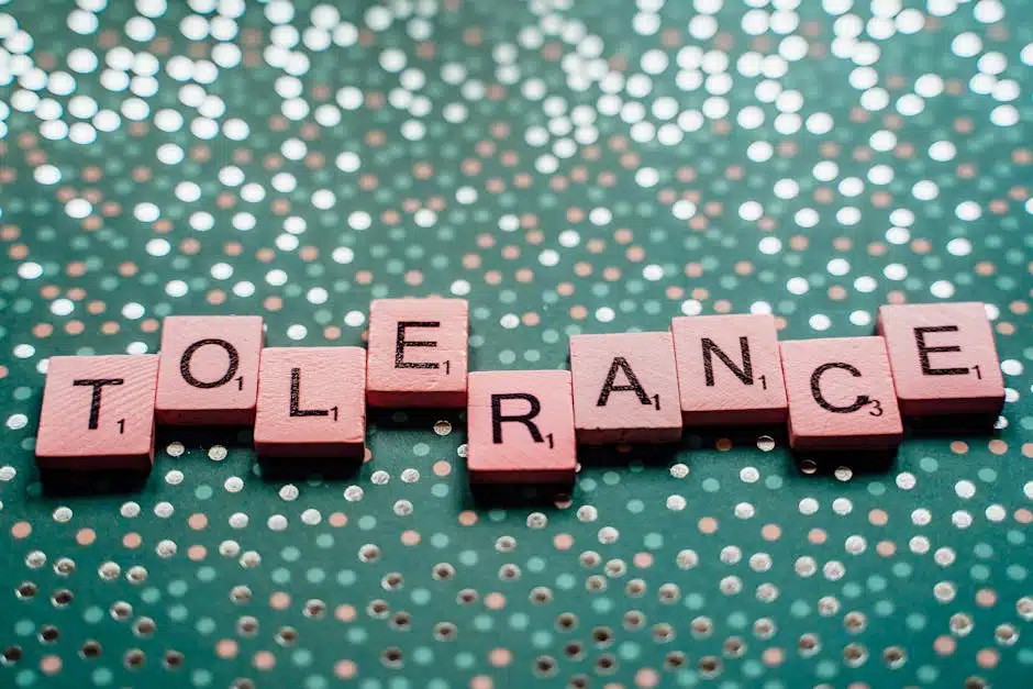 Close-up of scrabble tiles spelling 'tolerance' on a turquoise background.