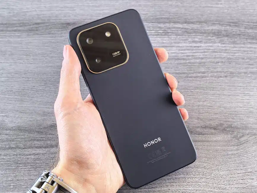 Close-up of a person holding a black smartphone with visible camera setup, shot on a wooden surface.