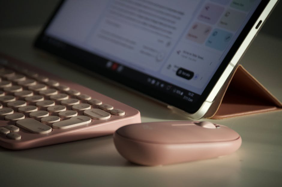 Stylish digital workspace setup with a pink keyboard and mouse beside a tablet.